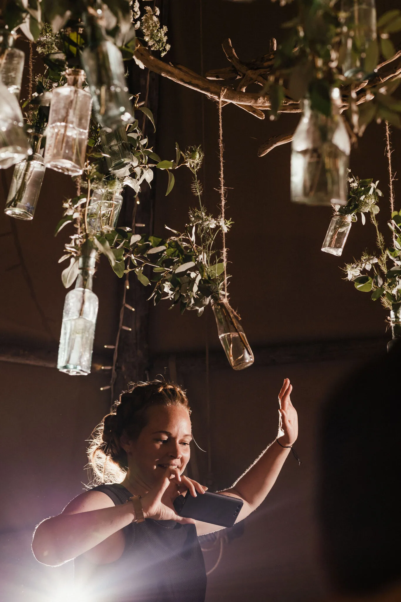 Guest dancing under a bottle and foliage chandelier inside a Yorkshire tipi